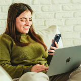 A woman with a smartphone and a laptop.
